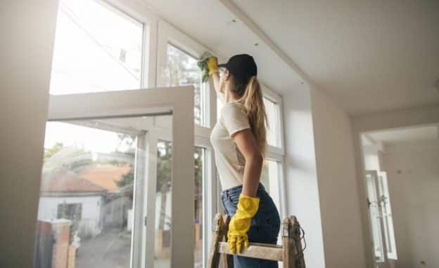 une femme pose un survitrage dans une maison en construction